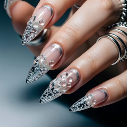 Long stiletto nails with a clear base and intricate 3D bubble-like embellishments, accented by silver glitter cuticle lines, evoking a frosty, Winter Nails aesthetic.