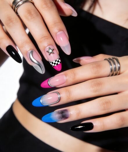 Close-up of hands showcasing a vibrant mix of edgy Nail Art Ideas, featuring checkerboard patterns, 3D embellishments, ombré blues and pinks, metallic accents, and glossy black polish.