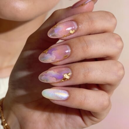 Pink And Gold Nails That Look Like Jewelry Long almond-shaped nails with a dreamy, translucent pink and gold design featuring soft pastel clouds and hints of iridescence.