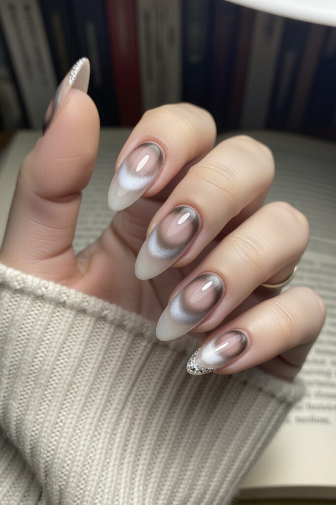 Almond-shaped acrylic nails with a smoky white and grey chrome ombré effect, accented by fine glitter on the tips, creating a frosty, dimensional look.