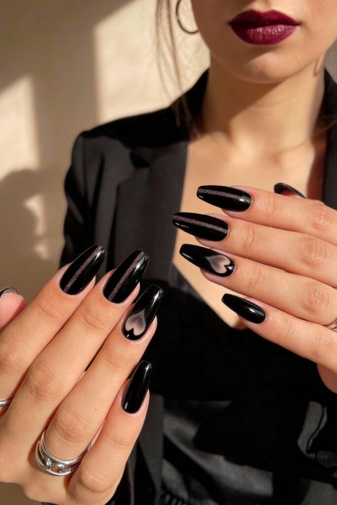 Black Valentines Day Nails That Feel Chic And Romantic 1 Woman with dark lipstick showing both hands with black valentines day nails, featuring glossy finishes and subtle heart-shaped accents in a smoke-like design on ring fingers.