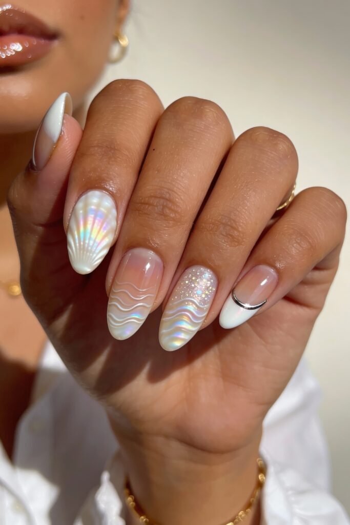 3d Nail Art Ideas That Look Luxe and Wearable 18 Almond nails with a white and translucent base, adorned with iridescent 3d nail art of seashells and wavy patterns, plus glitter and metallic accents for a mermaid-like effect.