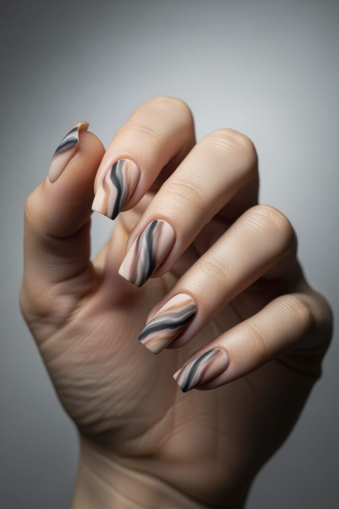 Matte square acrylic nails with wavy nude, beige, and black swirl designs, offering a modern, artistic aesthetic.