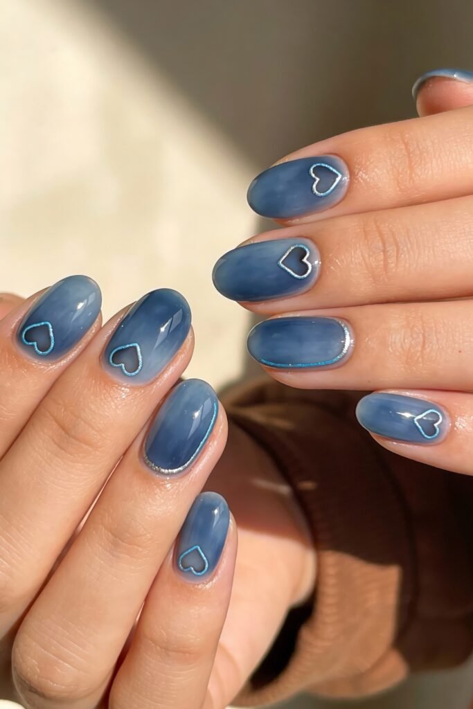 Rounded glossy nails in a muted blue tone, each nail accented with thin silver or blue heart outlines for a soft, romantic blue valentine nails design.