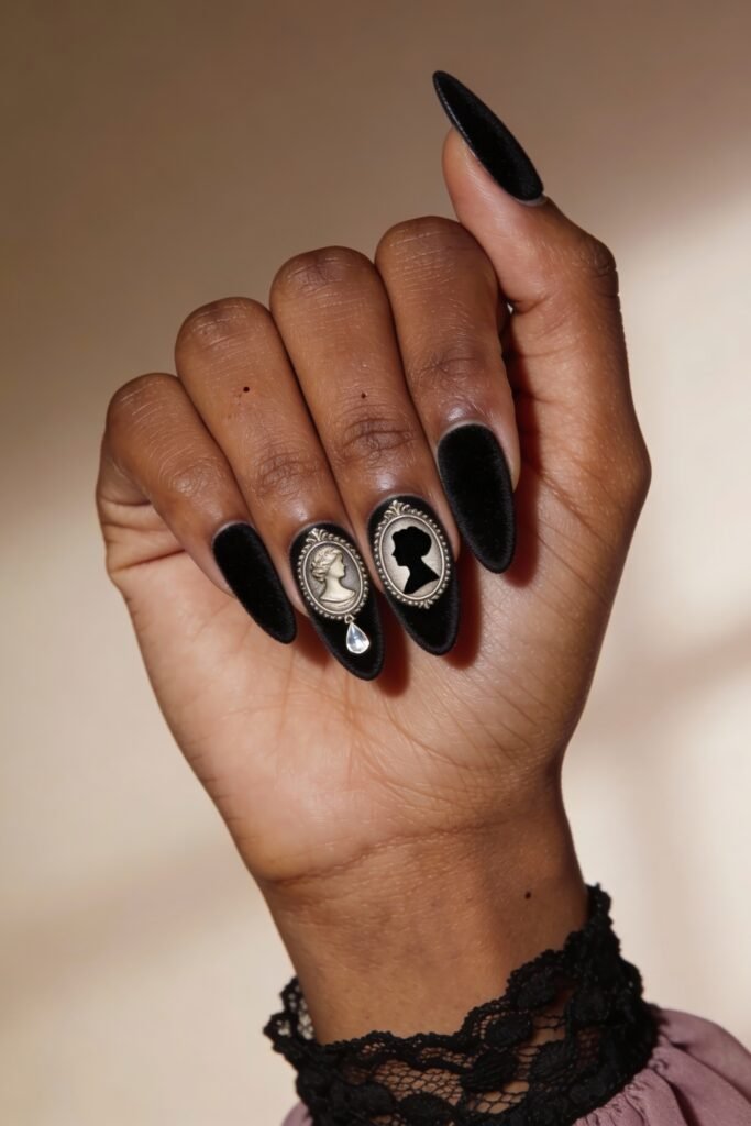 Gothic Valentines Nails That Feel Dark and Romantic 18 Almond-shaped gothic valentines nails in matte black, featuring metallic cameo silhouettes on the middle fingers with a delicate crystal drop.