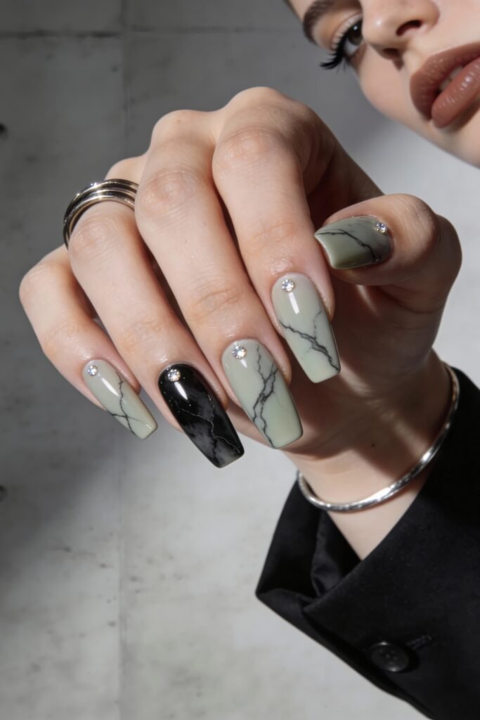 Square-shaped nails in muted green and black marble design, decorated with sparkling rhinestones, creating a sleek and modern street style nails look.