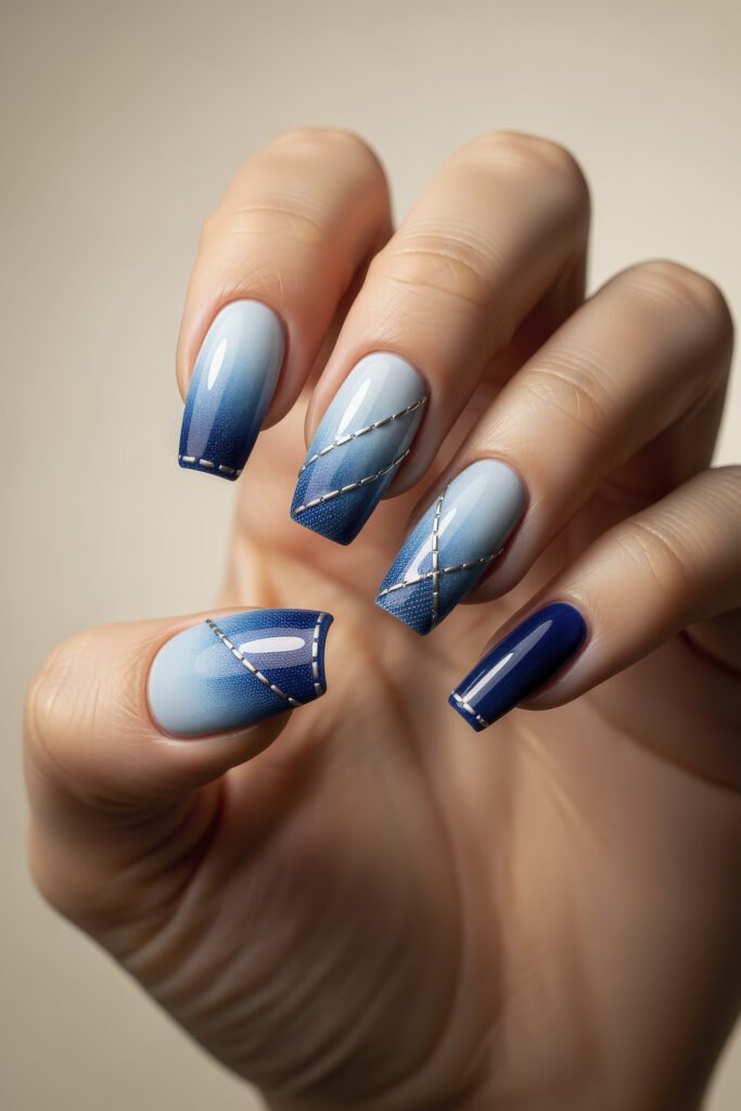 Glossy square acrylic nails with a gradient ombré from pale blue to navy, detailed with silver diagonal lines for a denim-inspired nail design.