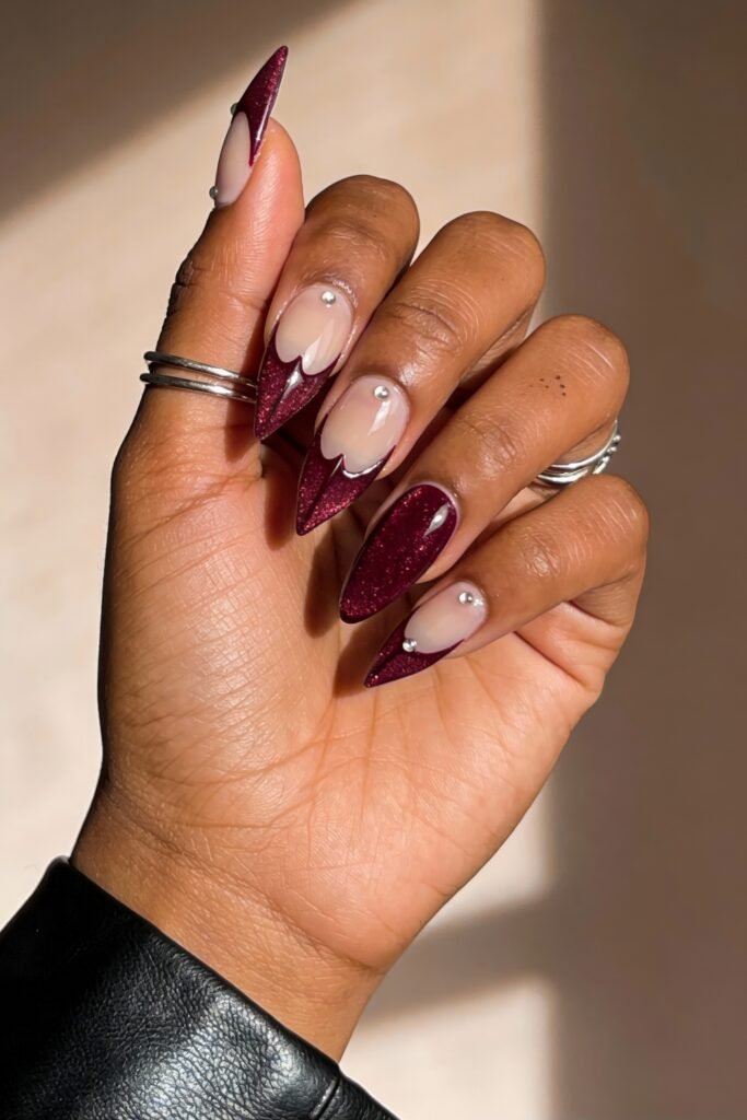 Gothic Valentines Nails That Feel Dark and Romantic 19 Deep burgundy glitter gothic valentines nails with dramatic stiletto tips and scalloped French designs, finished with small silver studs.