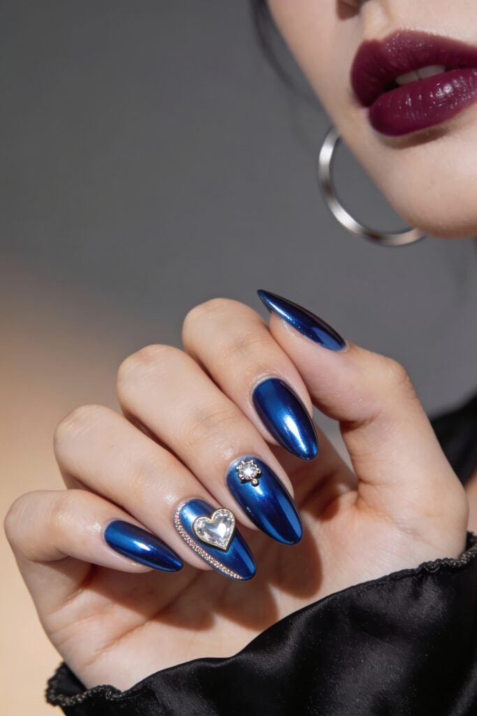 Shimmering chrome blue almond nails adorned with a crystal heart charm and gem accents, delivering a glamorous and luxurious blue valentine nails style.