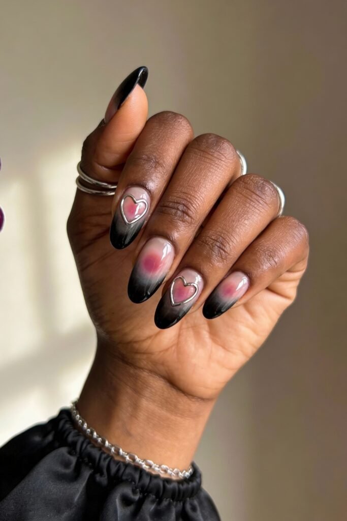 Black Valentines Day Nails That Feel Chic And Romantic 24 Almond-shaped nails with a soft pink to black gradient, decorated with metallic pink hearts outlined in silver, creating a romantic and moody valentines day vibe.