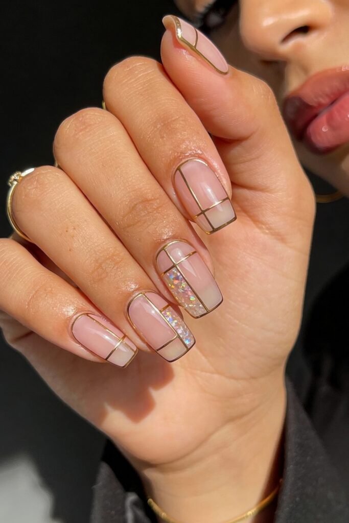 Square-shaped pink and gold nails bordered in metallic gold, some with iridescent or glittery sections creating a stained-glass effect.