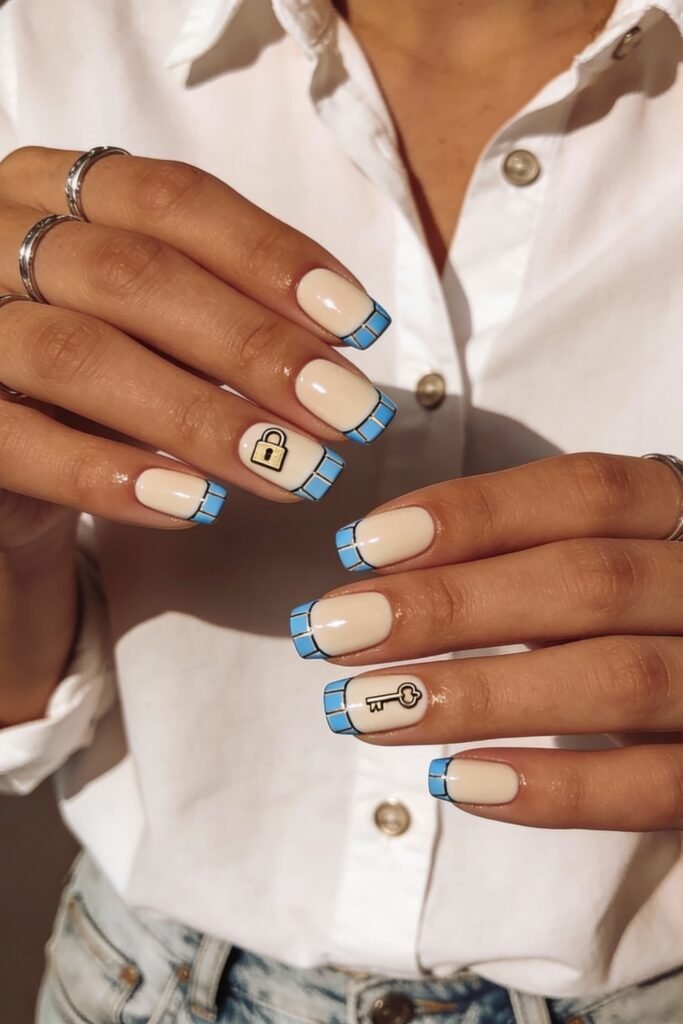 Glossy square nails with pale nude base and vibrant blue grid-style French tips, detailed with cute lock and key icons to symbolize love and connection in a blue valentine nails theme.