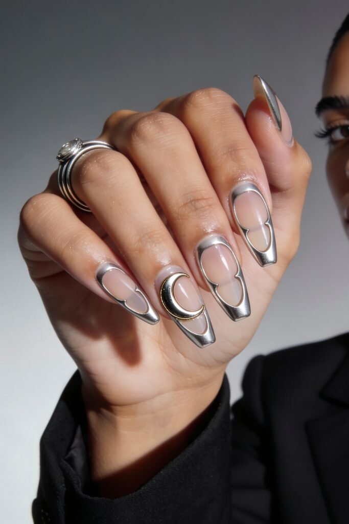 Sculptural chrome silver nails with negative space and a central gold crescent moon charm, blending edgy Nail Art Ideas with celestial elegance.
