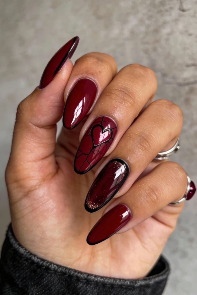 Gothic Valentines Nails That Feel Dark and Romantic 24 Deep burgundy gothic valentines nails with black outlines and a cracked heart motif, blending glossy and shimmer finishes with dramatic detail.