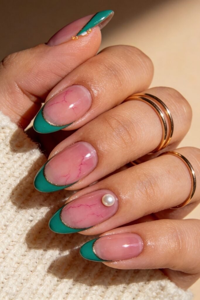 Almond-shaped nails with a glossy pink marble effect and deep green French tips outlined in gold, featuring a single pearl embellishment for a chic pink and green nails look.