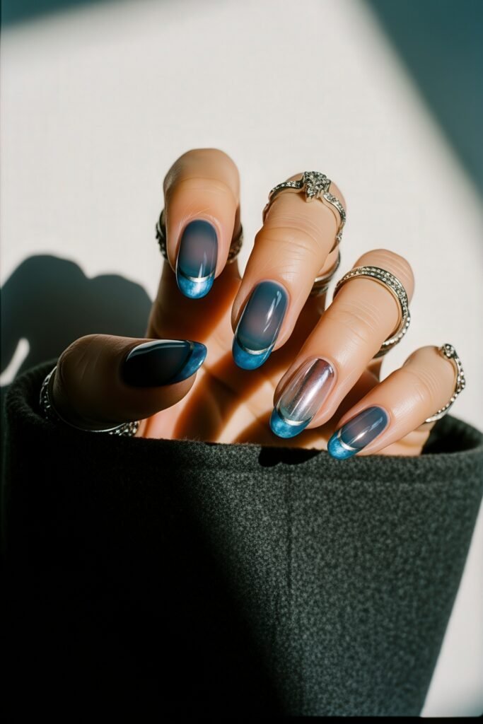Medium-length nails with a gradient of navy to clear blue tips, highlighted by white accents and a touch of shimmer, offering a cool, wintry vibe.