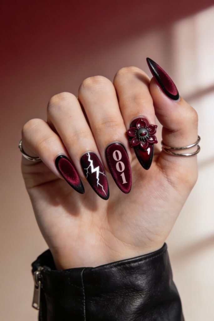 Deep red almond-shaped nails with black tips, showcasing lightning bolts, bold “001” text, and a 3D Demogorgon-inspired flower design, all reflecting a dark Stranger Things theme.