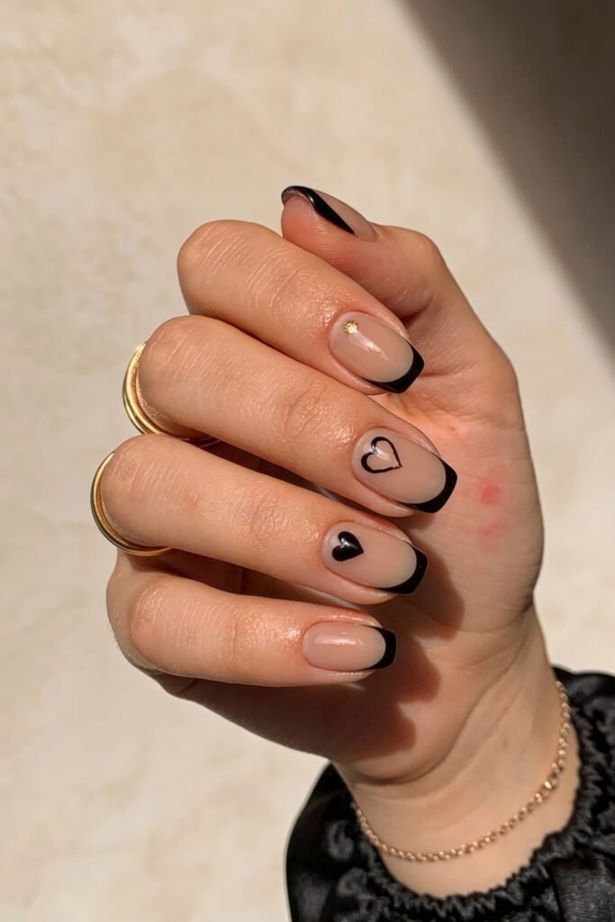 Black Valentines Day Nails That Feel Chic And Romantic 3 Nude nails with glossy black french tips and minimalist heart designs in black, perfect for a subtle and sweet black valentines day nail aesthetic.
