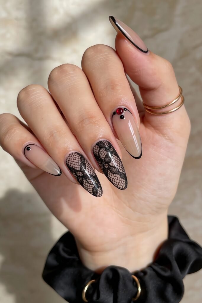 Black Valentines Day Nails That Feel Chic And Romantic 4 Elegant black valentines day nails on a nude base with black french tips, red and black rhinestones, and intricate lace-style detailing on two accent nails.