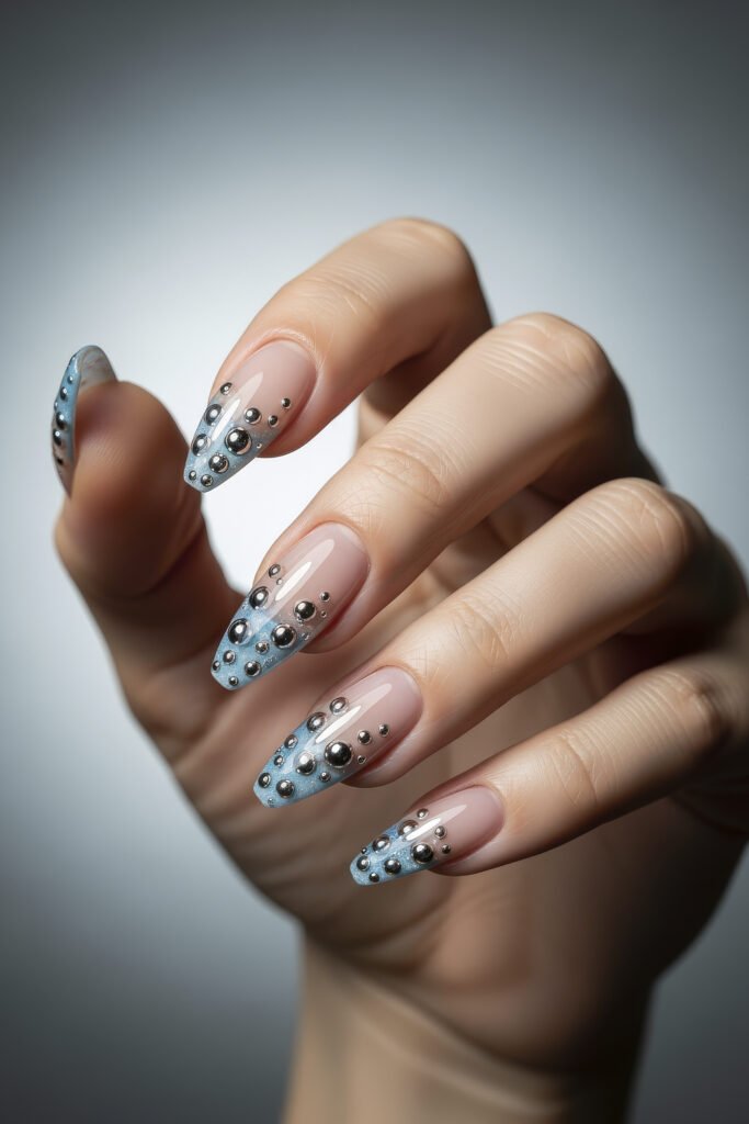 Almond-shaped acrylic nails with a light blue ombré and scattered chrome bubble accents, offering a bold and futuristic style.