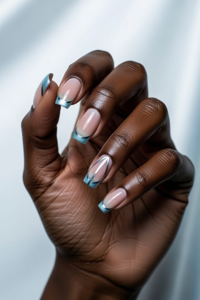 Hand with squared nails painted in sheer nude and icy blue French tips, with subtle silver accents and one crisscrossed line design, giving a clean and stylish Winter Nails vibe.