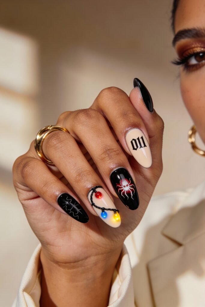 Mixed black and nude nails with bold Stranger Things elements, including “011” text, a red and white spider, lightning bolts, and Christmas light strands, worn with gold rings.