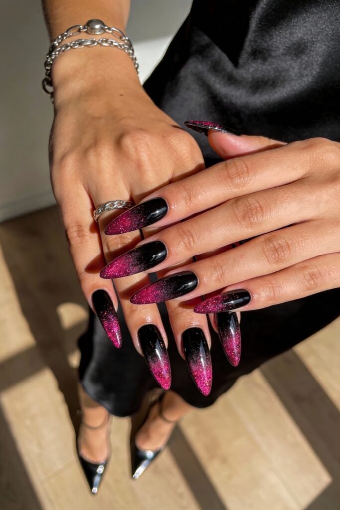 Black And Pink Nails That Look Instantly Chic 6 Black stiletto nails with pink glitter ombré tips, displayed under natural light, creating a dramatic and glamorous black and pink nails aesthetic.