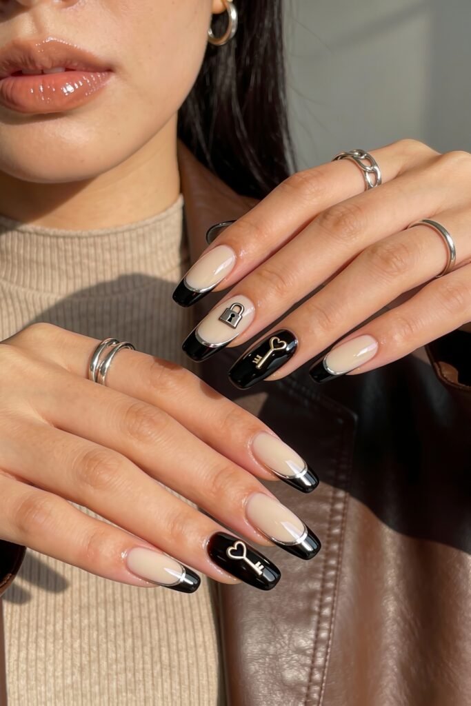 Black Valentines Day Nails That Feel Chic And Romantic 7 Nude and black valentines day nails with metallic french tips and feature nails decorated with 3D lock and key charms, styled with silver rings for a chic finish.