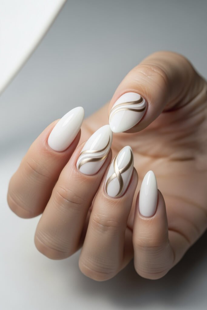 Milky White With Chrome Nails That Look Luxe 8 Almond-shaped nails in a white glossy finish, with select nails featuring smooth, gold-toned wavy line art for a clean, modern look.