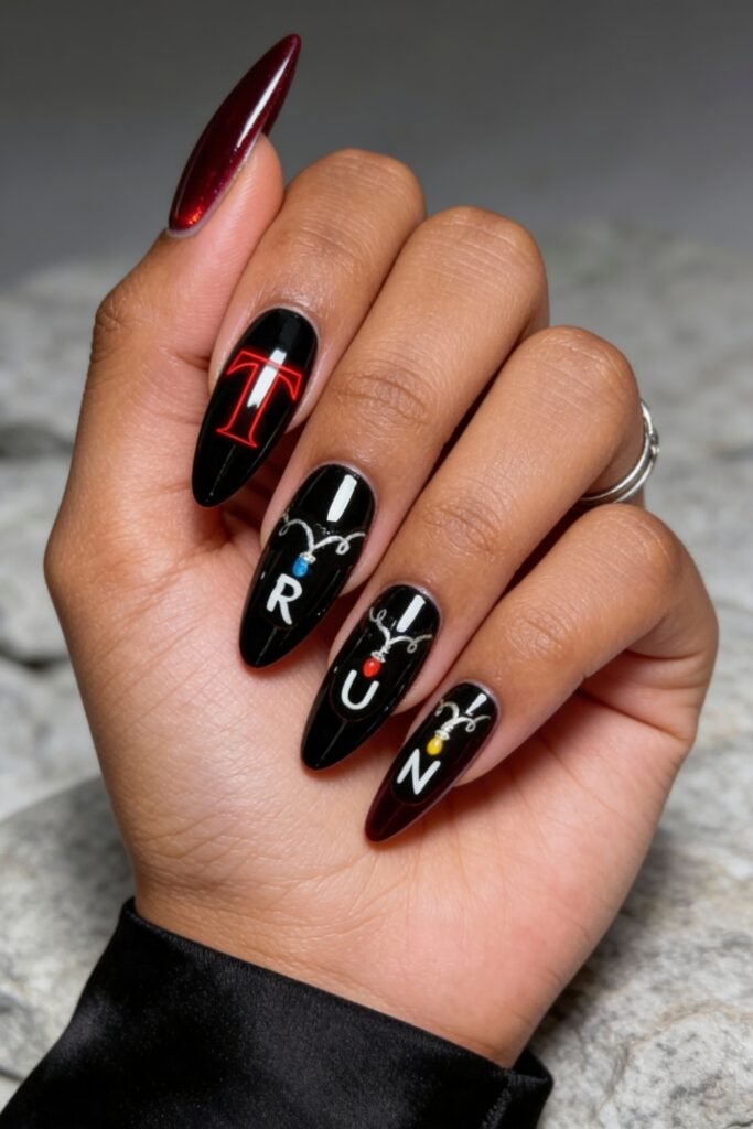Black and burgundy Stranger Things nails spelling out “RUN” with string light details and a bold red “T,” all on a glossy finish with a stiletto shape.