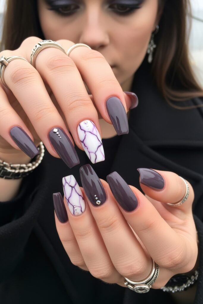 Long square nails in a glossy plum shade, paired with white marble accent nails featuring fine purple veining and tiny rhinestones, delivering a luxurious purple winter nails design.