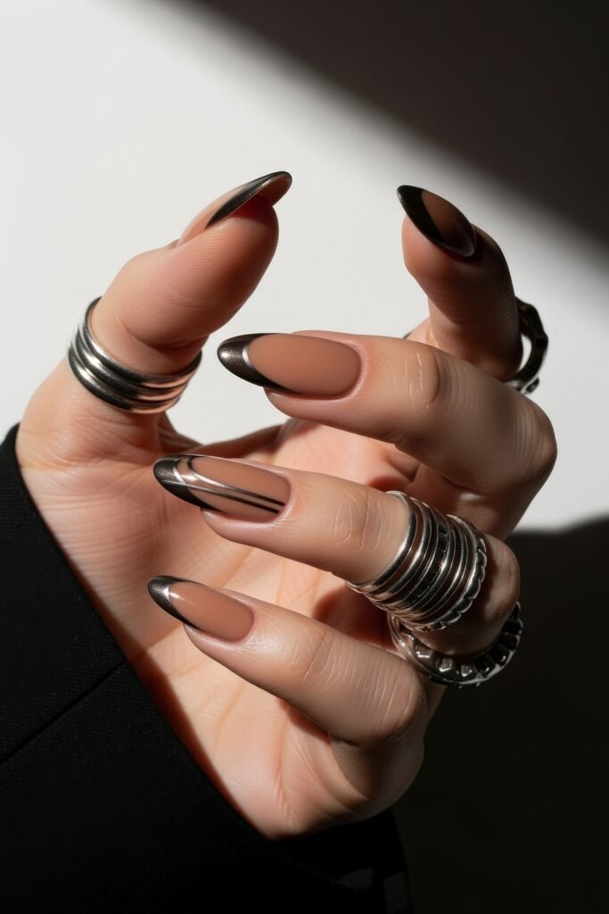 Almond nails with a warm nude base and sleek black chrome tips, featuring minimalist accent lines for a bold, modern January nails look.