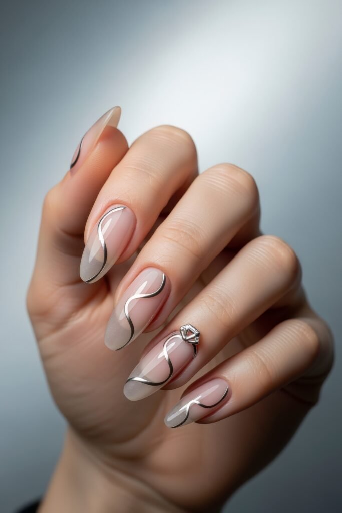 Fresh, Luxe Spring Nail Designs You’ll Want to Save 11 Elegant translucent nails with silver chrome swirls and a 3D gemstone accent, blending minimalism with soft metallic spring nail designs.