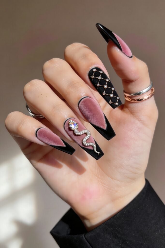 Black And Pink Nails That Look Instantly Chic 9 Square-shaped velvet-textured nails in dusty pink and black, featuring an ornate snake charm on one finger and a crisscross pearl-studded pattern on another, blending luxury and edge in a bold black and pink nails design.