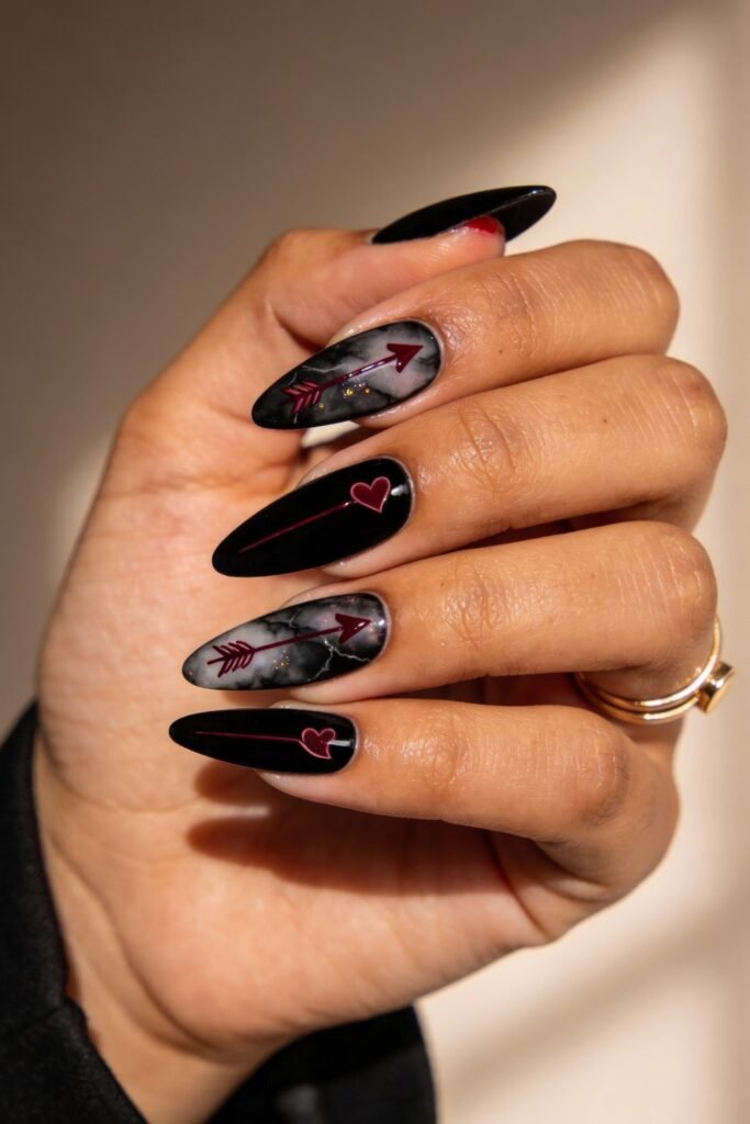 Black Valentines Day Nails That Feel Chic And Romantic 10 Almond-shaped black valentines day nails with a mix of solid black and marble-effect designs, each adorned with red heart arrows for a playful, romantic look.