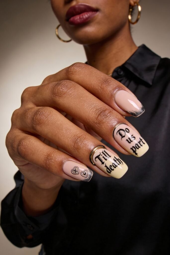 Gothic Valentines Nails That Feel Dark and Romantic 10 Square gothic valentines nails with a matte nude base and black ombré tips, featuring bold gothic script reading "Till death do us part" and metallic hearts and rings as accents.