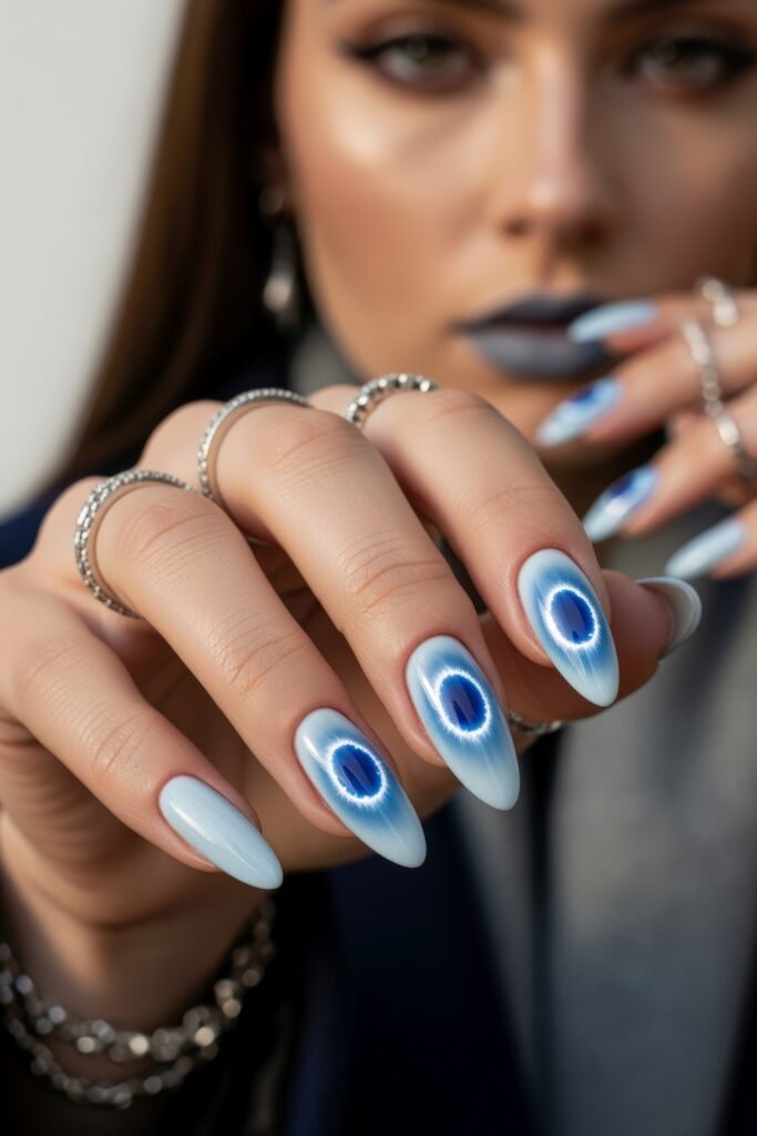 Hand with almond-shaped nails featuring a striking icy blue base and deep navy circular designs resembling frozen crystals, capturing a bold Winter Nails style.