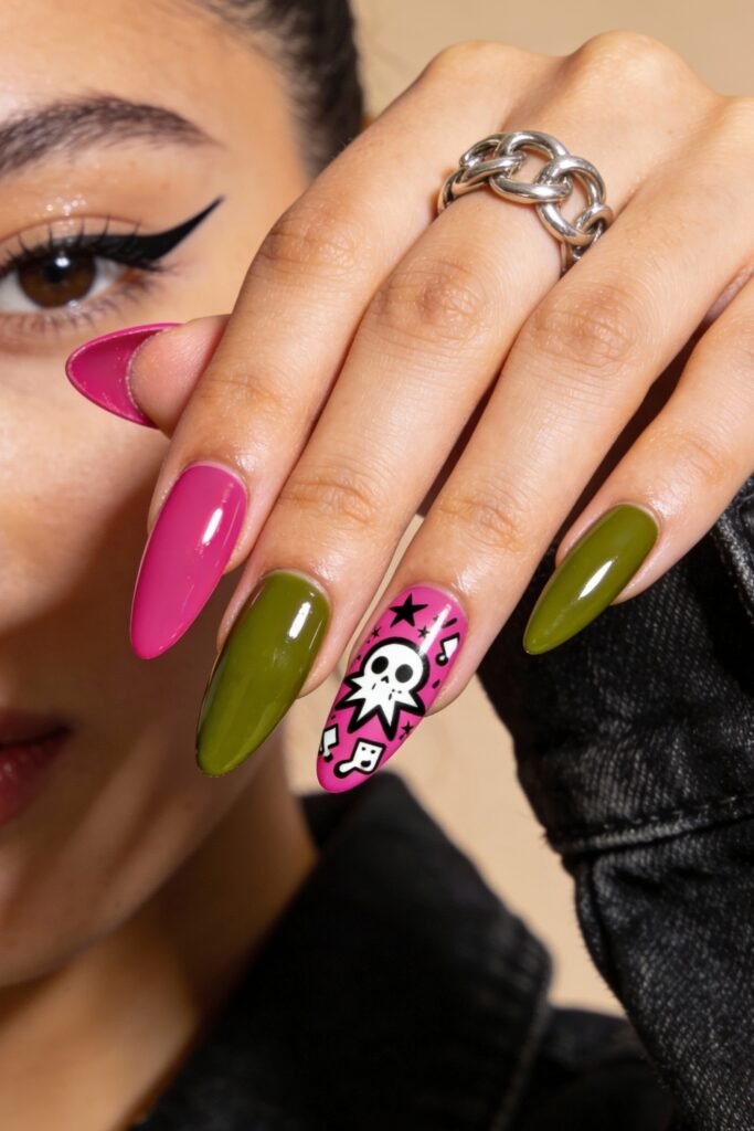 Almond-shaped nails painted in glossy hot pink and deep green, featuring bold graphic accents like a white skull, stars, and music notes for an edgy pink and green nails statement.