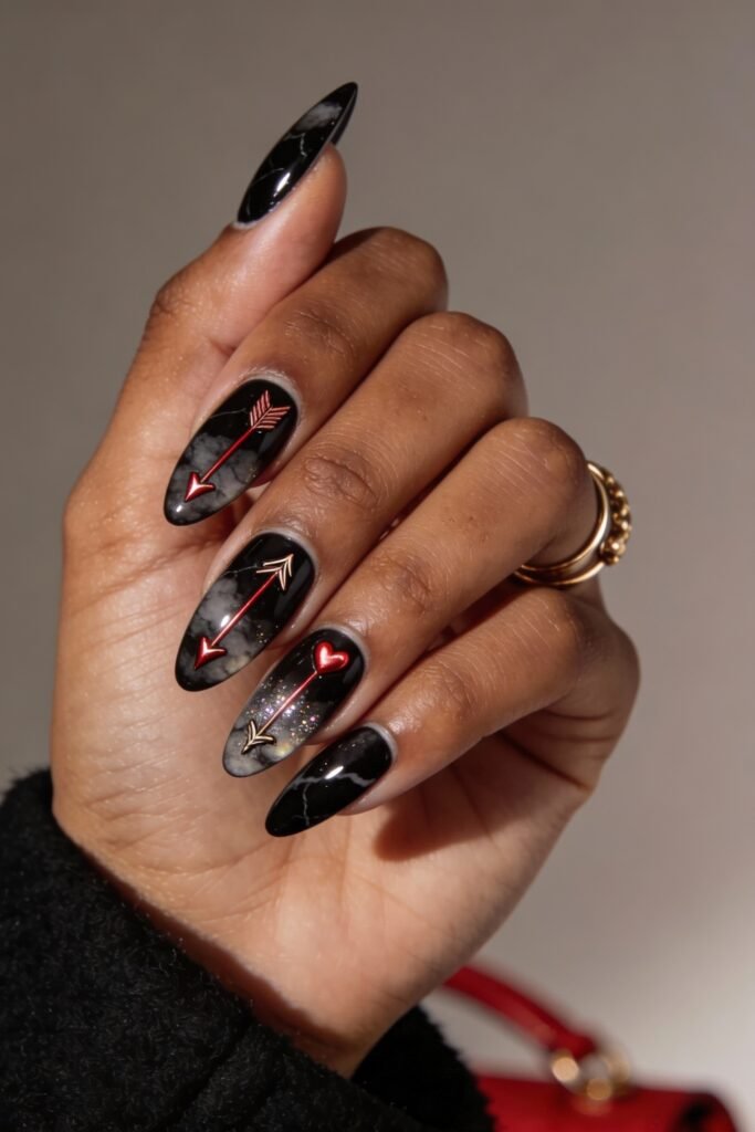 Black Valentines Day Nails That Feel Chic And Romantic 11 Glossy black valentines day nails with a smoky marble finish, decorated with red and gold Cupid-style arrows and a glowing red heart accent on the ring finger.
