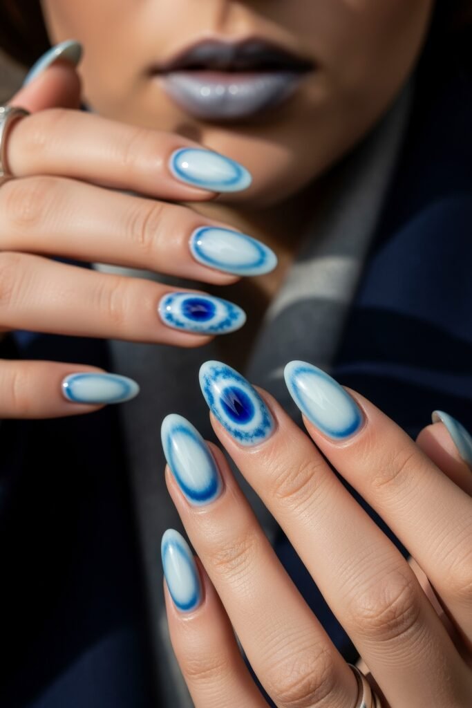 Close-up of hands with oval nails painted in a soft frosty blue, with accent nails showcasing intricate blue burst patterns for a unique icy blue winter nails look.
