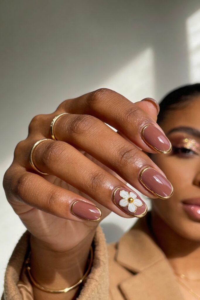 Mauve nails with a glossy finish, outlined in gold, and one accent nail featuring a white daisy with a gold center.