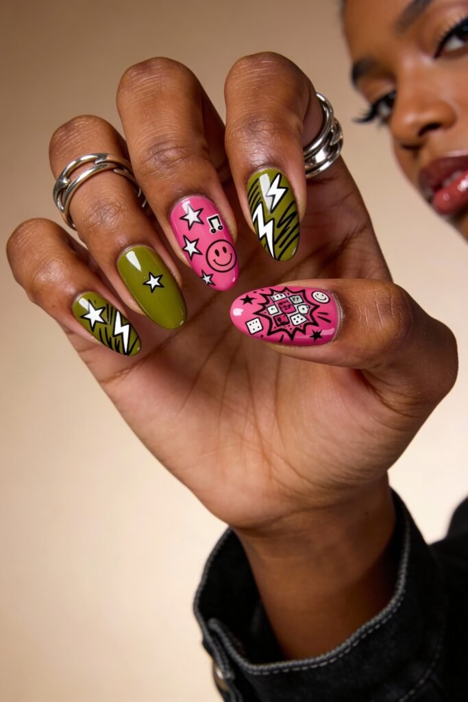 Round nails with a matte pink and olive green color scheme, decorated with bold black-and-white graphic icons like stars, lightning bolts, dice, and smiley faces for a punk-inspired pink and green nails look.
