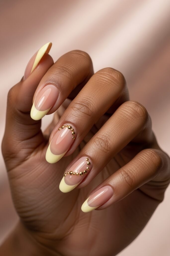 Fresh, Luxe Spring Nail Designs You’ll Want to Save 14 Almond nails with pastel yellow tips and curved gold bead accents on nude polish, combining minimal elegance and sunny spring energy.