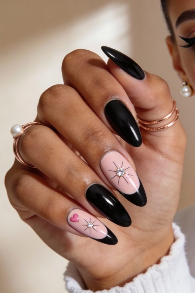 Black And Pink Nails That Look Instantly Chic 12 A black and pink nails look with a reversed French design: glossy black tips over nude pink bases, enhanced with sparkling starburst gems and a small pink heart accent.