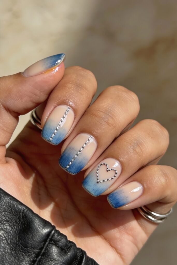 Short square nails with a faded blue ombré and stitched silver lines, finished with a heart outlined in thread-like detailing for a soft, textured blue valentine nails look.