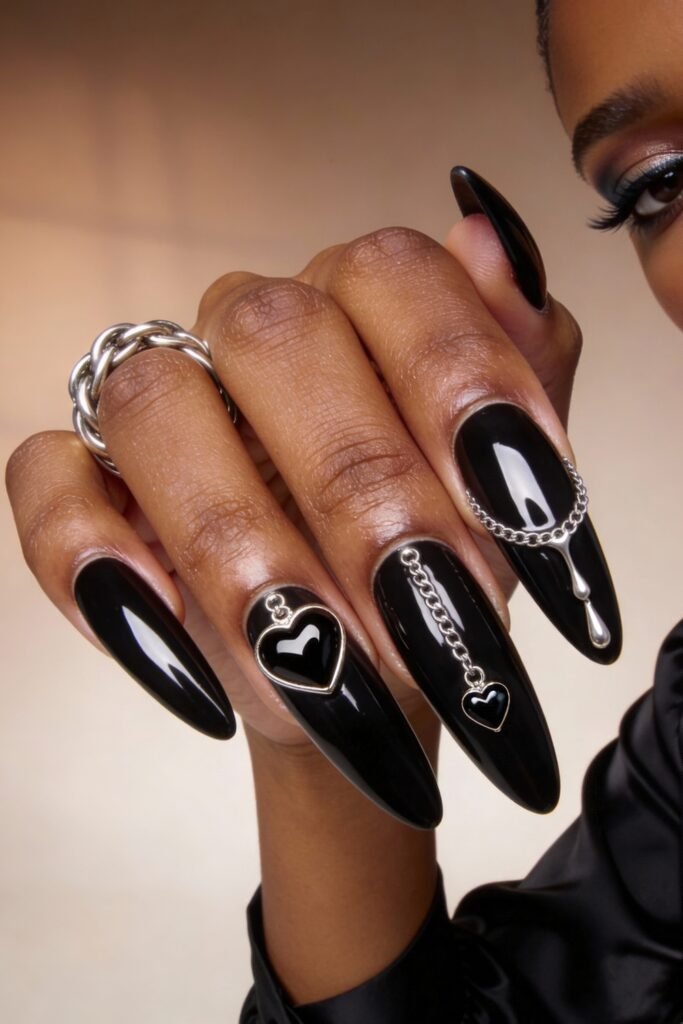 Gothic Valentines Nails That Feel Dark and Romantic 15 Long almond gothic valentines nails in glossy black, decorated with silver heart frames, dangling chains, and metallic teardrop accents.