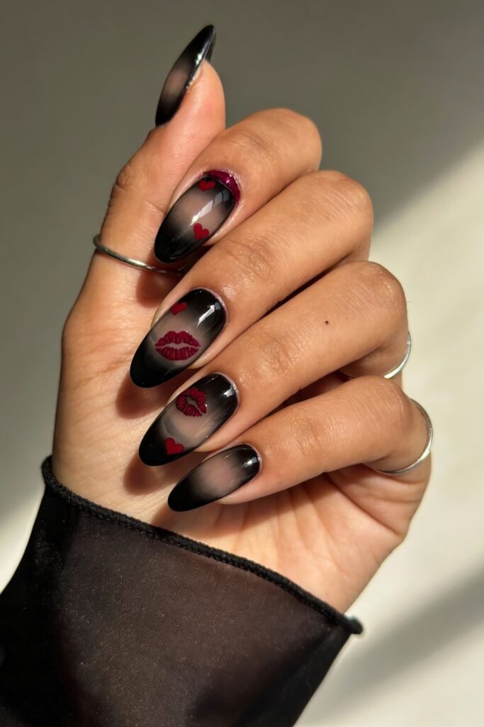 Gothic Valentines Nails That Feel Dark and Romantic 16 Black ombré gothic valentines nails with sheer tips, red heart and lip decals, and a bold red glitter cuticle accent on the index finger.