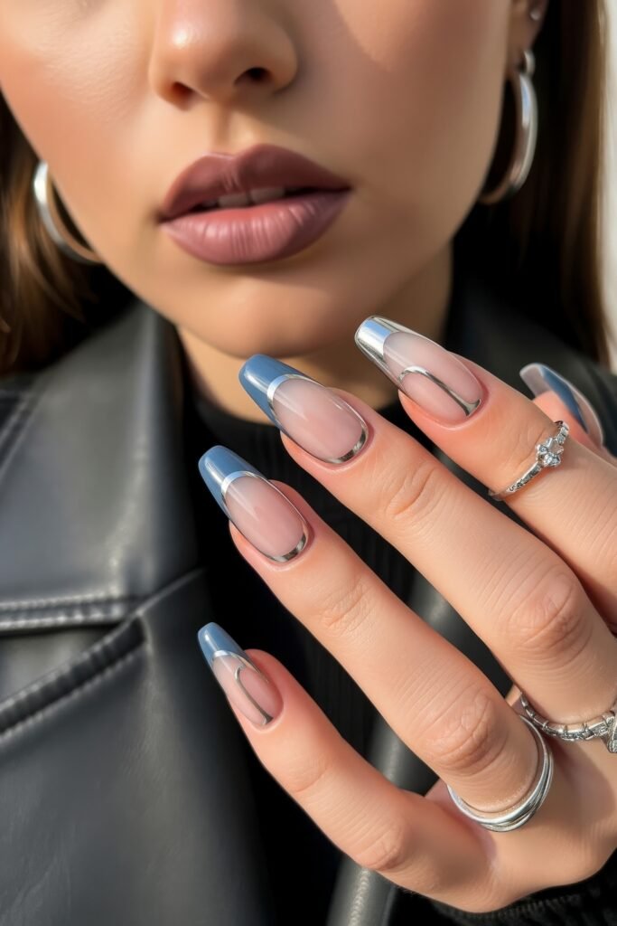 Hand with long square nails featuring a modern French tip in metallic silver and soft icy blue, outlined with chrome detailing for a sleek, winter-ready finish.