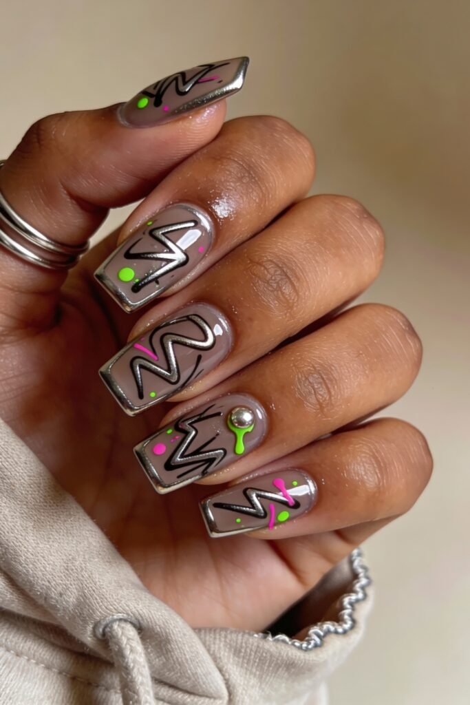 3d Nail Art Ideas That Look Luxe and Wearable 17 Square nails in taupe with electric 3d black zigzag patterns, neon splatters, and chrome borders, including a metallic bead on one nail for added dimension.