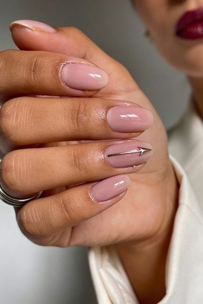 Pink Valentines Nails That Feel Chic, Glossy, and New 18 Neutral-toned glossy nails with a minimal metallic arrow design across the ring finger, giving a subtle Valentine's vibe.